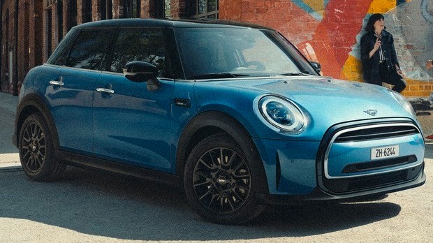 MINI Electric Une femme tout sourire descend d’une MINI Electric garée
